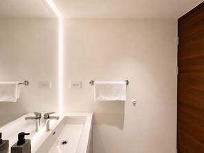 A modern bathroom with a large mirror, two sinks, and a wooden door. - Vrbo Property (San Salvador)