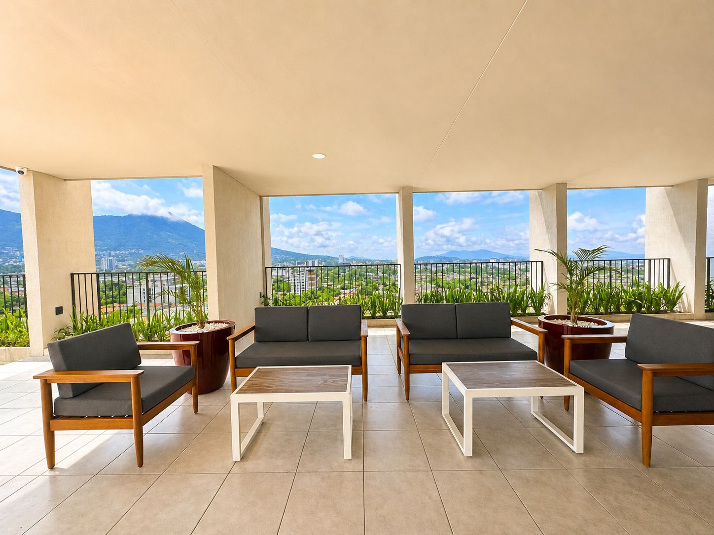 Un balcon agrémenté d’un canapé, de chaises et d’une table, offrant une vue sur un paysage urbain dominé par des montagnes.