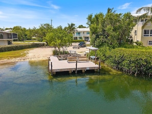A waterfront property with a dock, a boat, and a building in the background. - KeyLime Oasis - Private Pool, 3 Beds, 2 Baths, with Boat Parking (Tavernier)