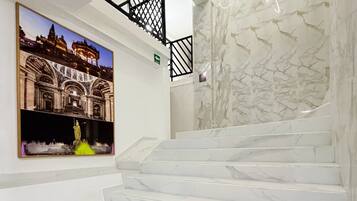 Una escalera con escalones de mármol blanco y barandilla de metal negro.