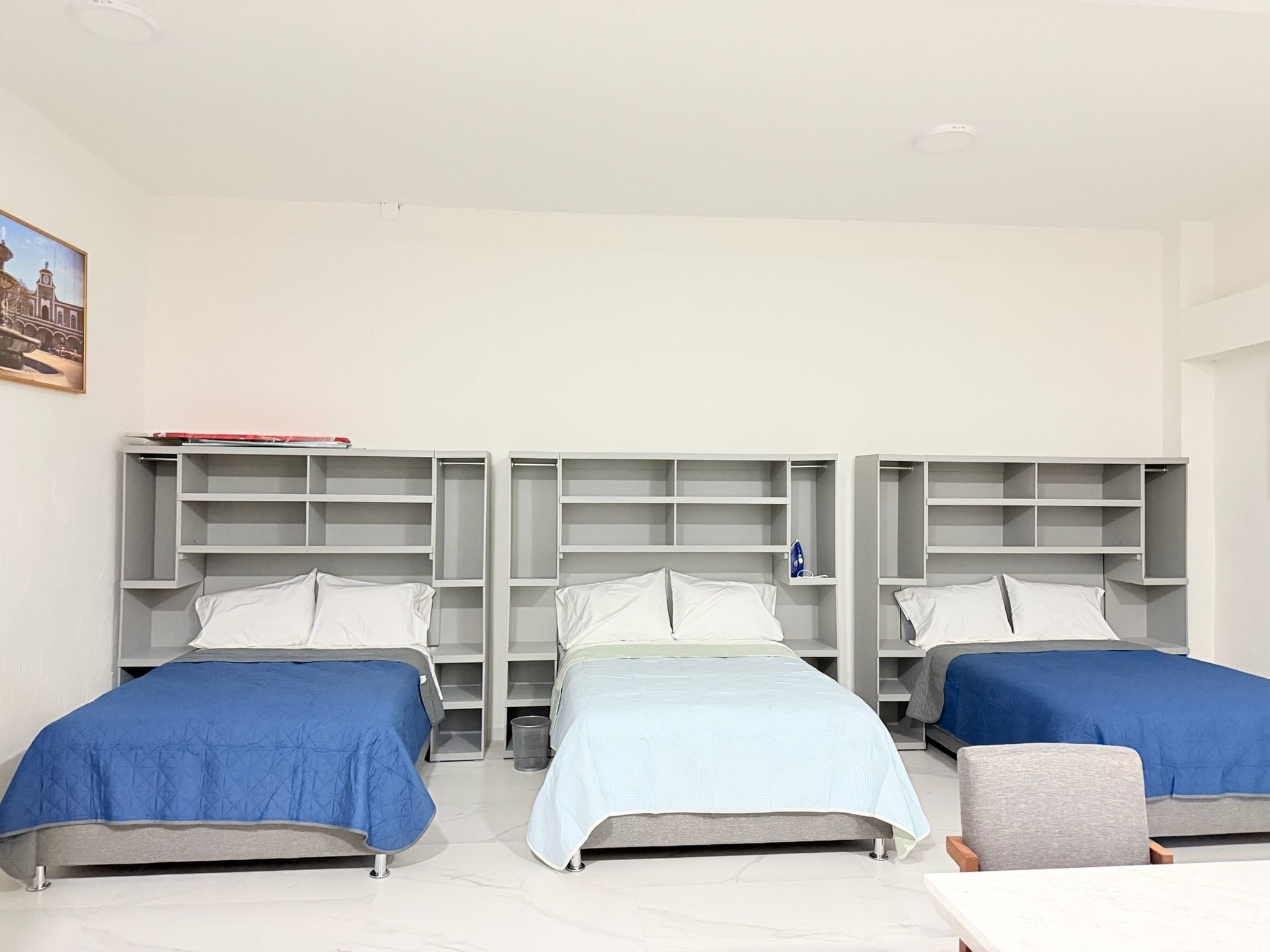 Una habitación de hotel con dos camas, una mesita pequeña y estantes empotrados.