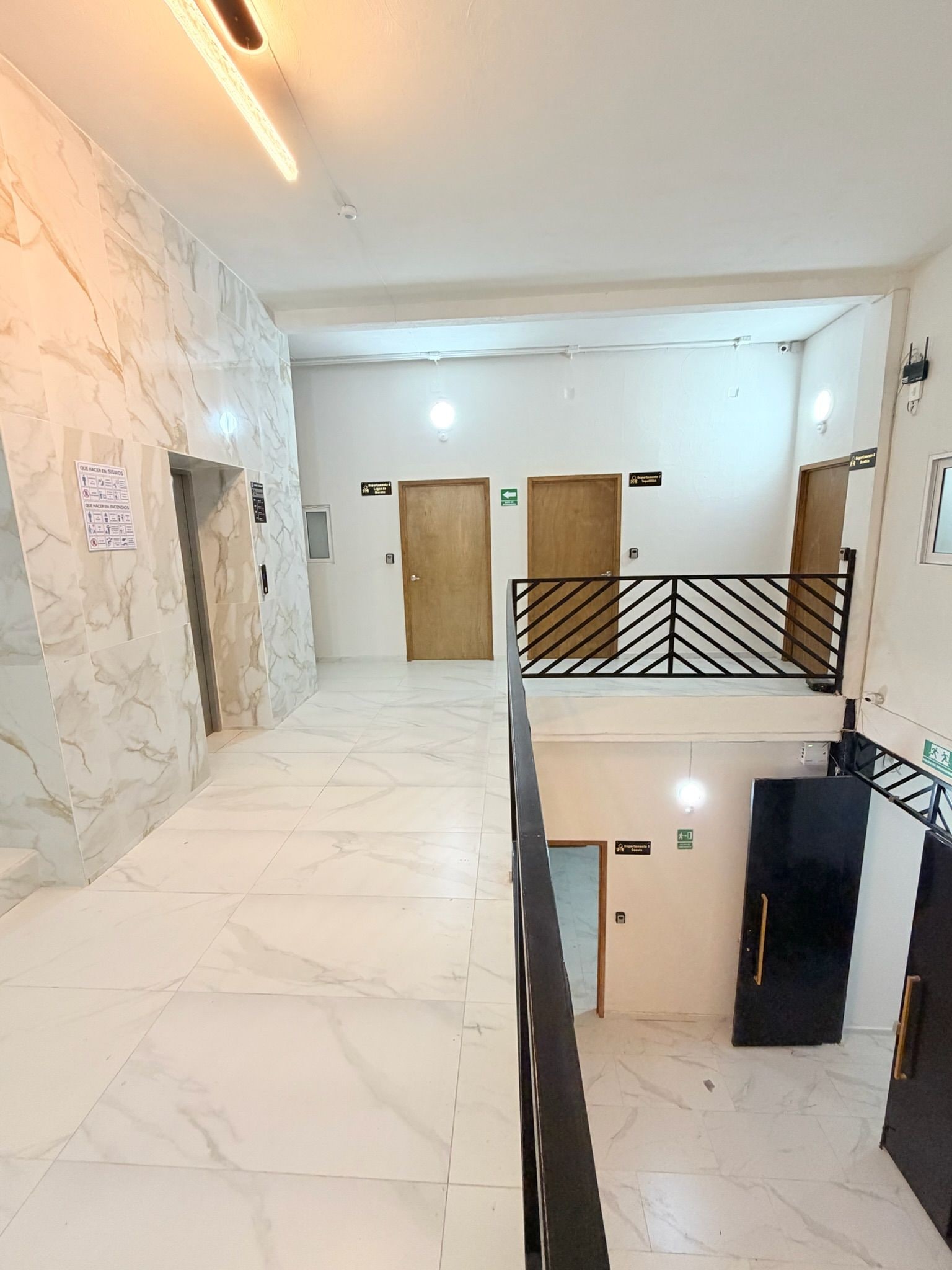 Un vestíbulo de hotel con suelo de mármol, una escalera y varias puertas.