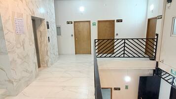 Un vestíbulo de hotel con suelo de mármol, una escalera y varias puertas.