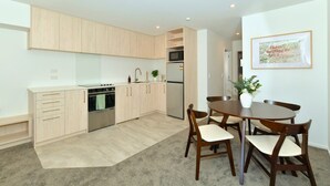 Una cocina moderna con armarios de madera clara, electrodomésticos de acero inoxidable y un comedor con una mesa redonda y sillas.