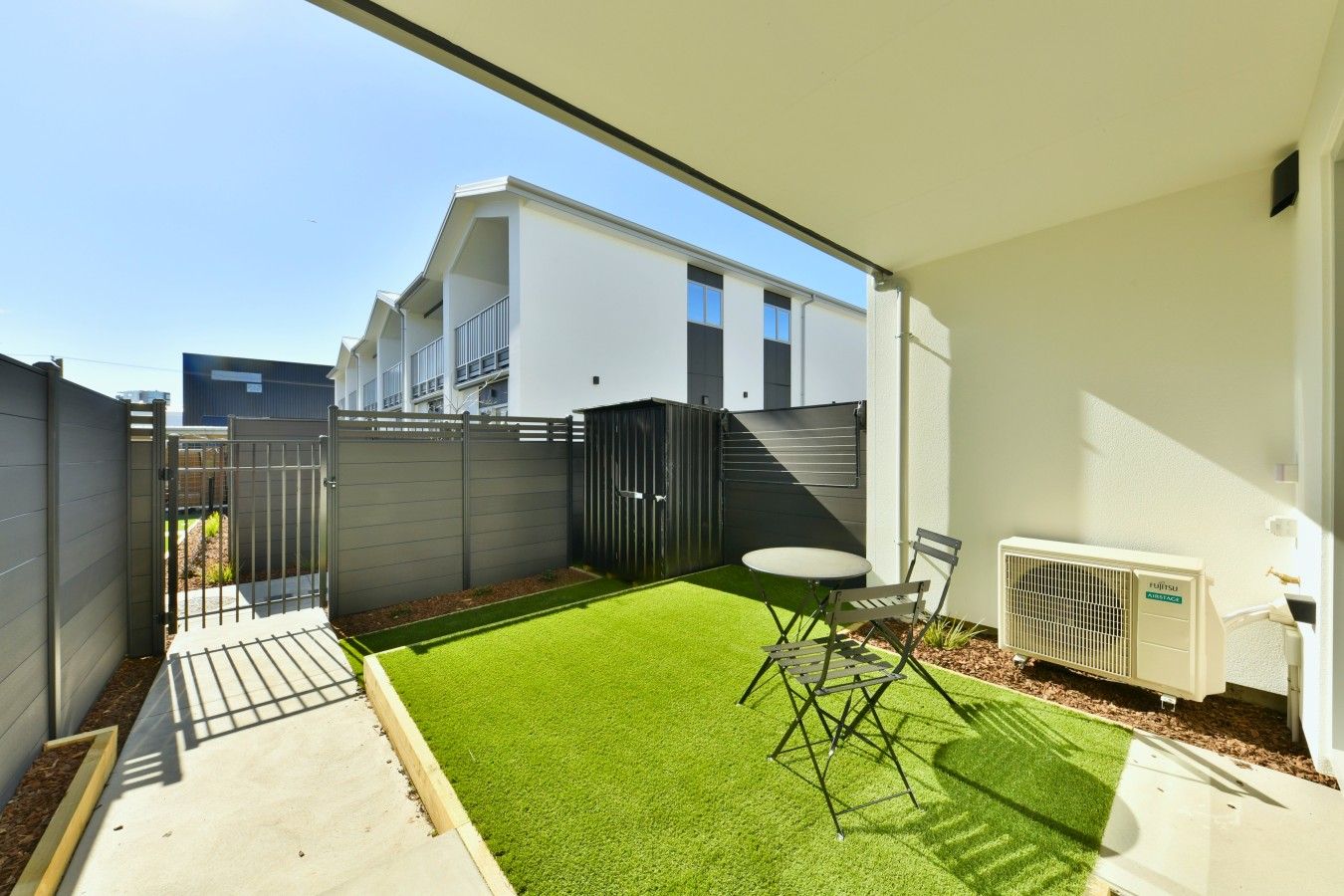 A modern outdoor patio with artificial grass, a folding table, and a chair.