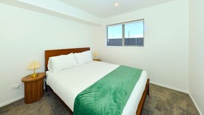 Un dormitorio con cama, dos lámparas de noche, una ventana y piso alfombrado.