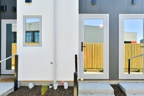 A modern building with a white facade, a set of double doors, and a small window. - Modern 1 Bedroom Apartment with Private Balcony (Christchurch)