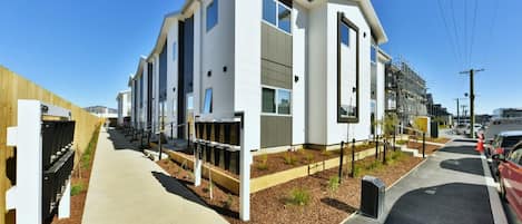 Un edificio moderno con techo plano, ventanas grandes y un sendero pavimentado.