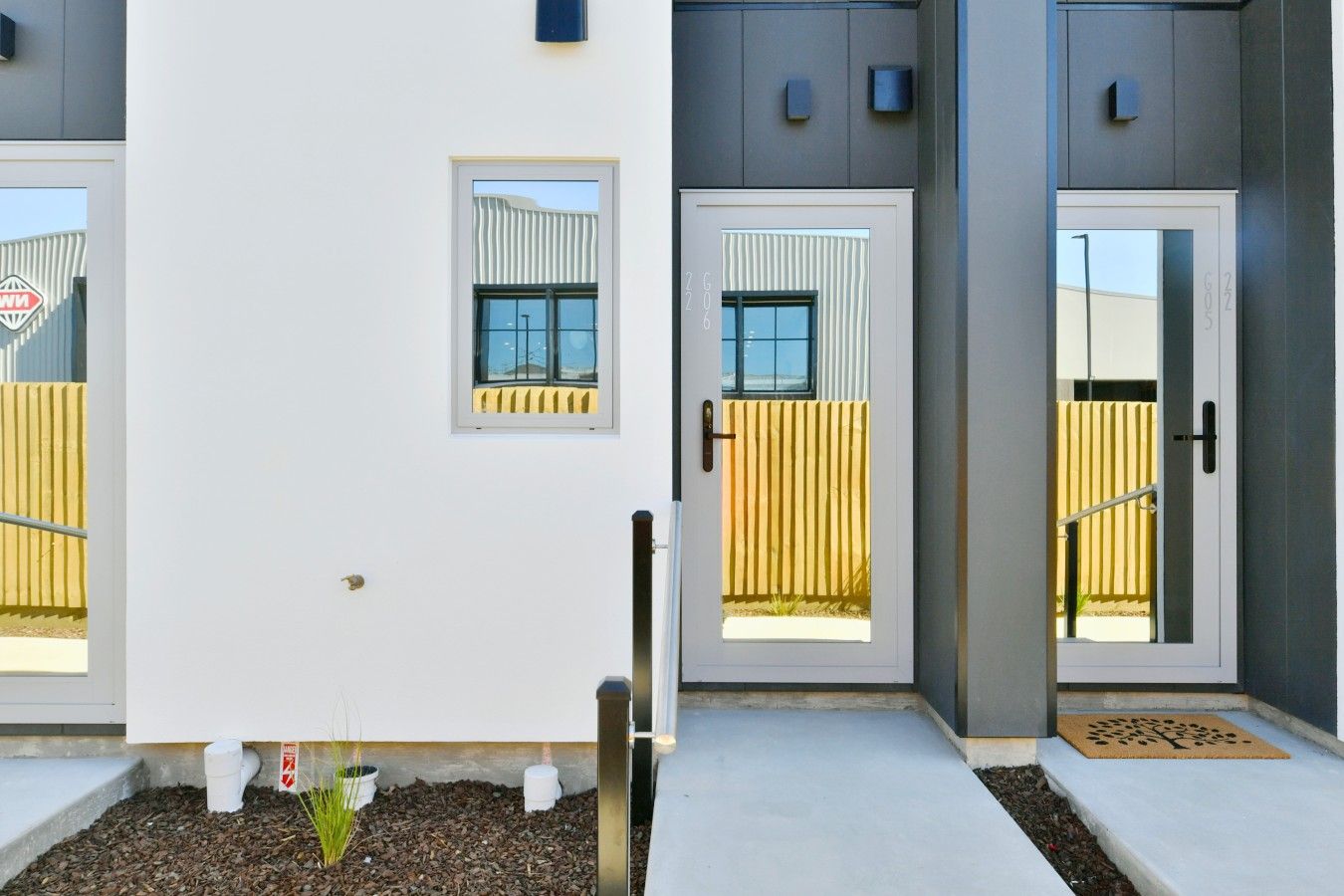 Un edificio moderno con tres puertas, cada una con un ventanal y un buzón pequeño encima.