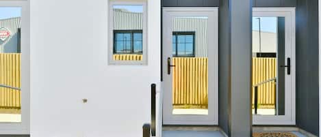 Un edificio moderno con tres puertas, cada una con un ventanal y un buzón pequeño encima.