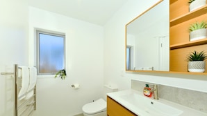 Ein modernes Badezimmer mit Toilette, Waschbecken und einem Fenster mit Pflanze.