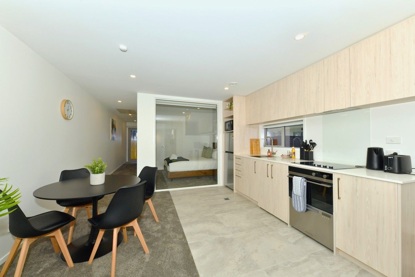Una cocina moderna con comedor, que incluye una mesa con sillas, un reloj en la pared y una planta.