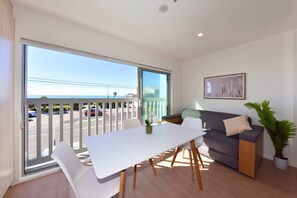 A modern living room with a balcony, a dining table, and a sofa. - The Marine Parade Haven with Private Parking (Christchurch)
