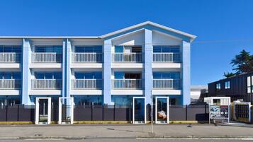 A multi-story building with balconies, a gated entrance, and a 'For Sale' sign.