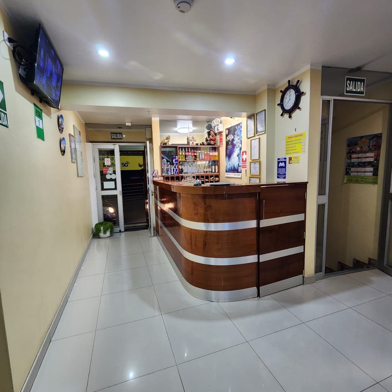 A reception area with a wooden reception desk, a clock, and a sign indicating the exit.
