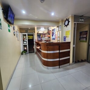 A reception area with a wooden reception desk, a clock, and a sign indicating the exit.