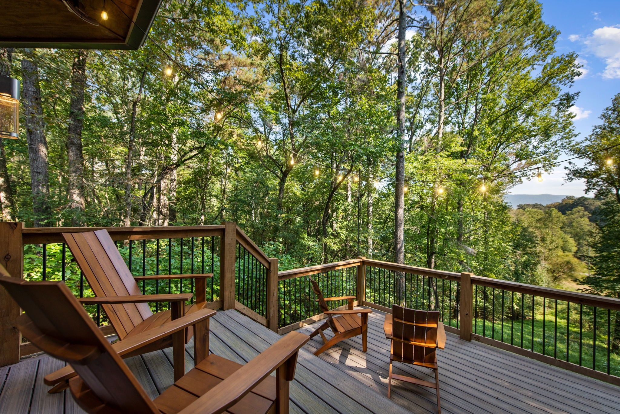 A wooden deck with outdoor furniture and a view of a forested area.
