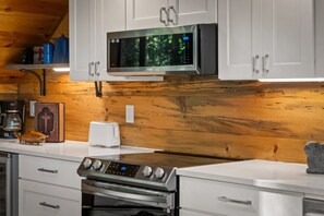 A kitchen with white cabinets, a stainless steel microwave, a toaster, and a stove.