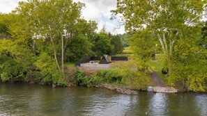 A riverside property with a modern outdoor seating area and a view of the water. - Juniata River Escape (McVeytown)