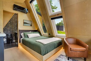 A bedroom with a sloped ceiling, a bed, a chair, and a window. - Juniata River Escape (McVeytown)