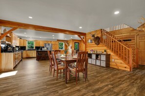 Ein geräumiges Blockhaus-Interieur mit Essbereich, Küche und einer Treppe.