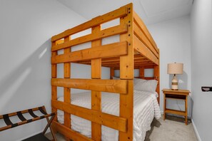 Ein Etagenbett mit Holzrahmen, ein Nachttisch mit Lampe und ein gestreifter Sessel.