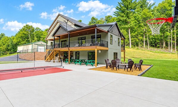 Ein zweistöckiges Gebäude mit Balkon, Außenbereich zum Sitzen und einem Basketballplatz.