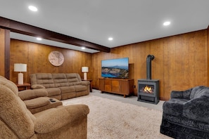 Ein gemütliches Wohnzimmer mit Kamin, Fernseher und bequemen Möbeln.
