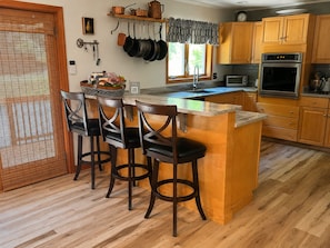 A kitchen with a central island, wooden cabinets, a microwave, and a stove.