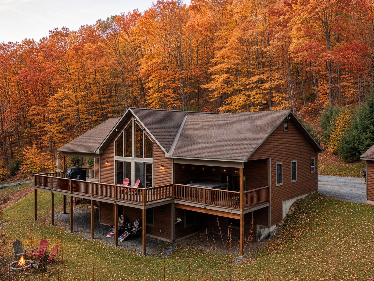 A two-story wooden cabin with a balcony, surrounded by autumn foliage.