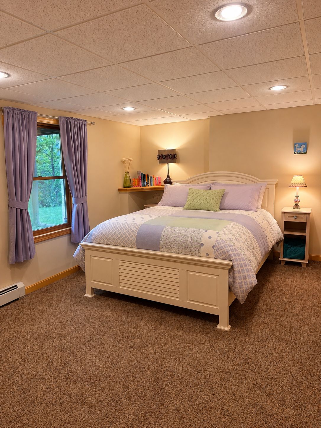 A bedroom with a bed, a nightstand, a lamp, a shelf with books, and a window with curtains.