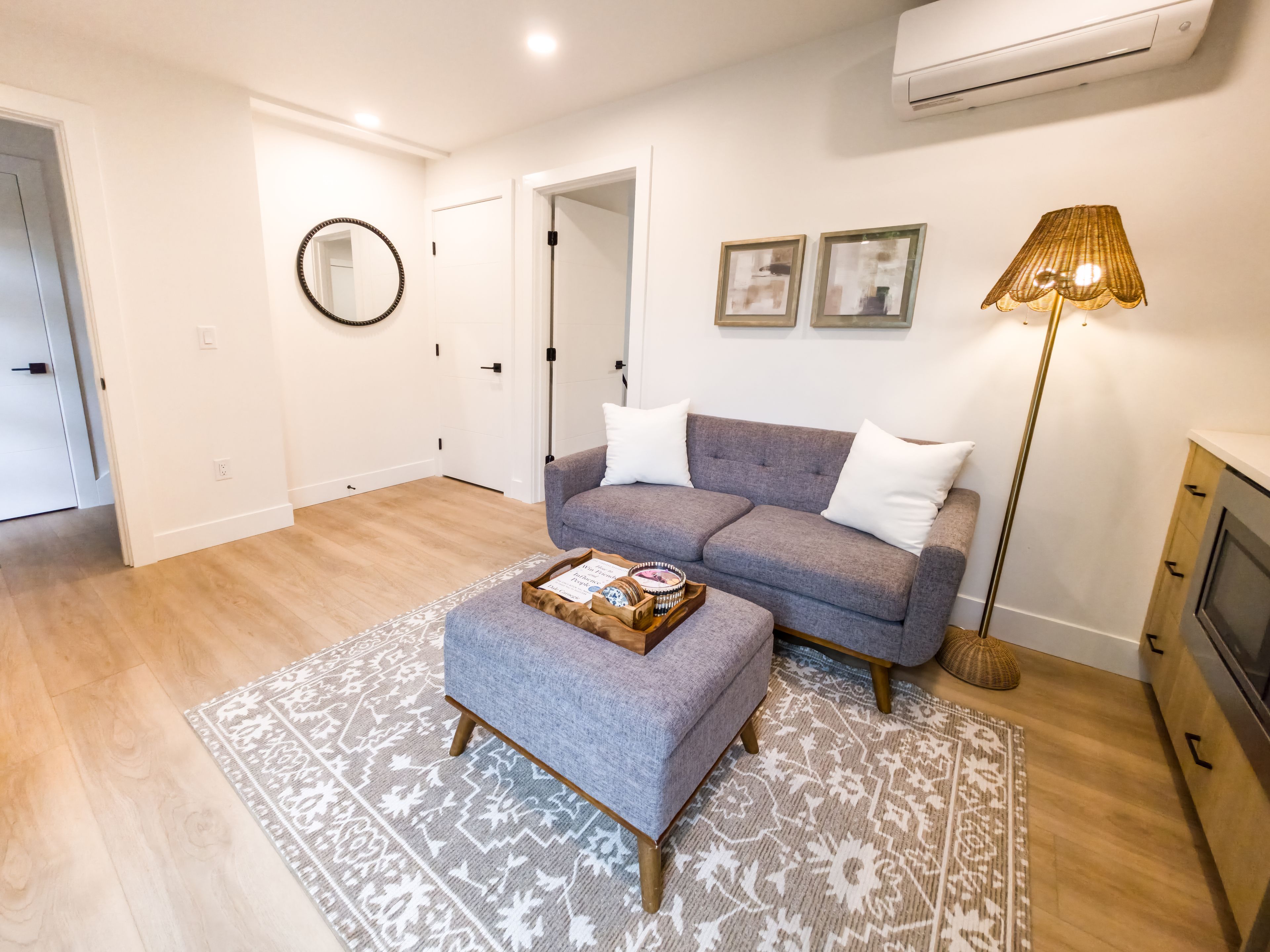 A modern living room with a grey sofa, a patterned rug, and a floor lamp.