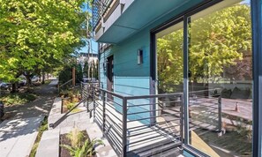 A modern building with a blue exterior, large windows, and a balcony with a metal railing. - Modern 3-bedroom Capitol Hill Home with Full Kitchen (Seattle)