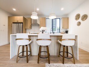 A modern kitchen with a central island, wooden cabinets, stainless steel appliances, and pendant lighting. - Modern 3-bedroom Capitol Hill Home with Full Kitchen (Seattle)