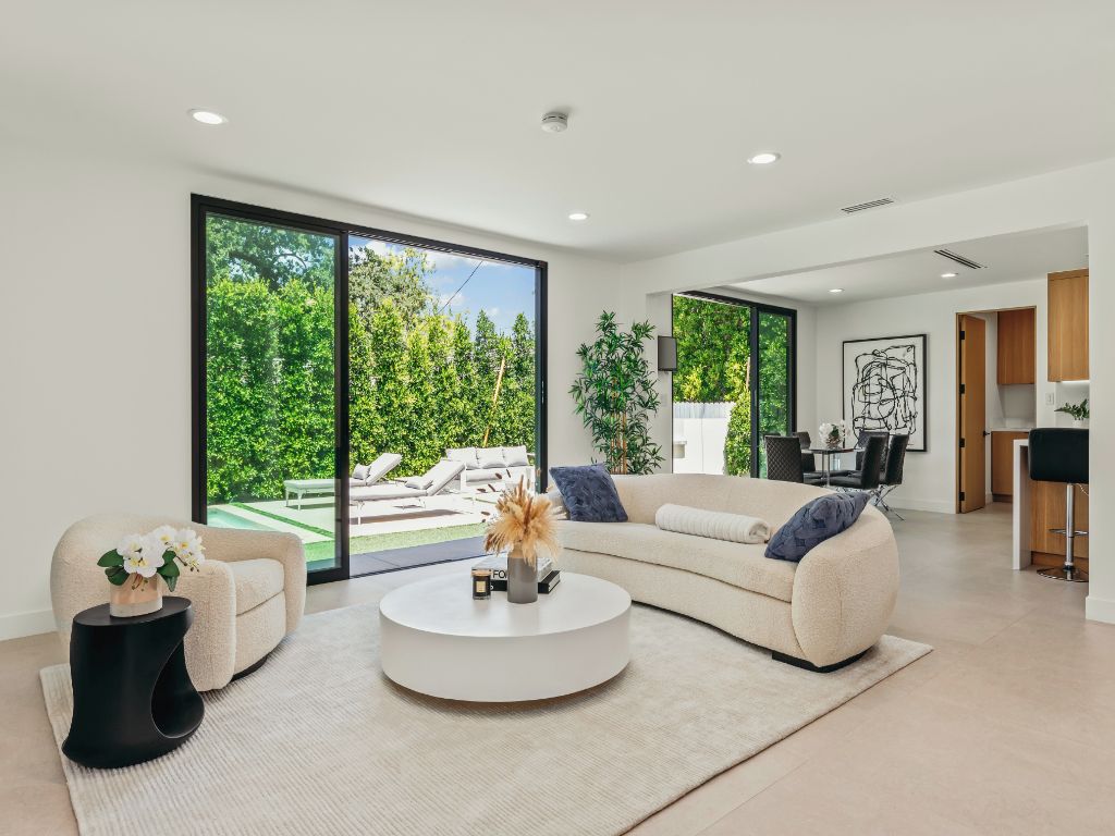 A modern living room with a large window, a round coffee table, and a beige sofa.