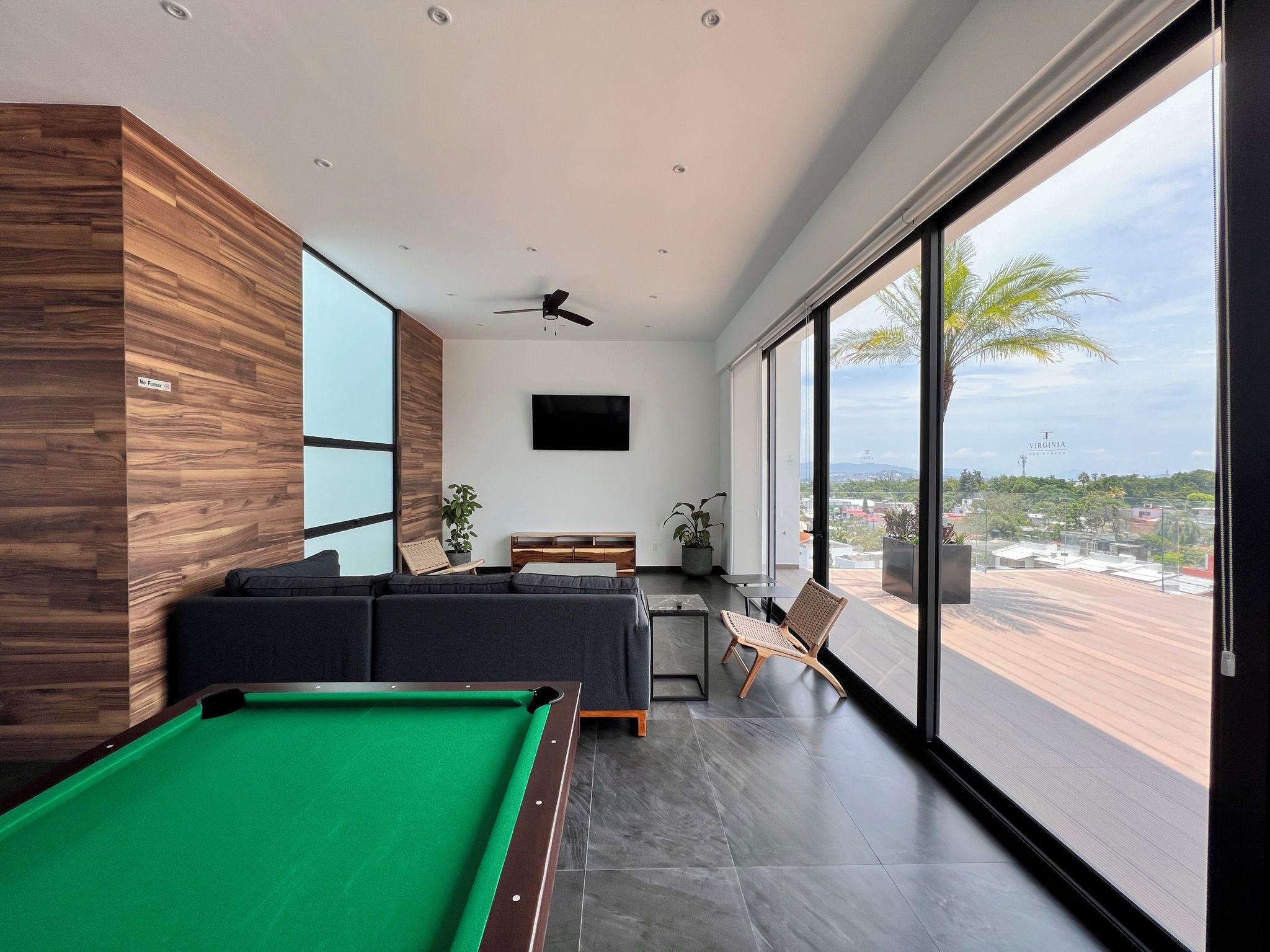 A modern living room with a pool table, a sofa, and a view of the city.
