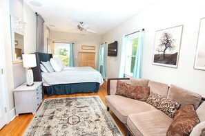 A bedroom with a bed, a dresser, a nightstand, a ceiling fan, a window with curtains, a wall-mounted TV, and a framed picture. - OCEANFRONT, Ocean & Sound Views, Priv Pool, SAUNA-PM3, Palmers View (Duck)