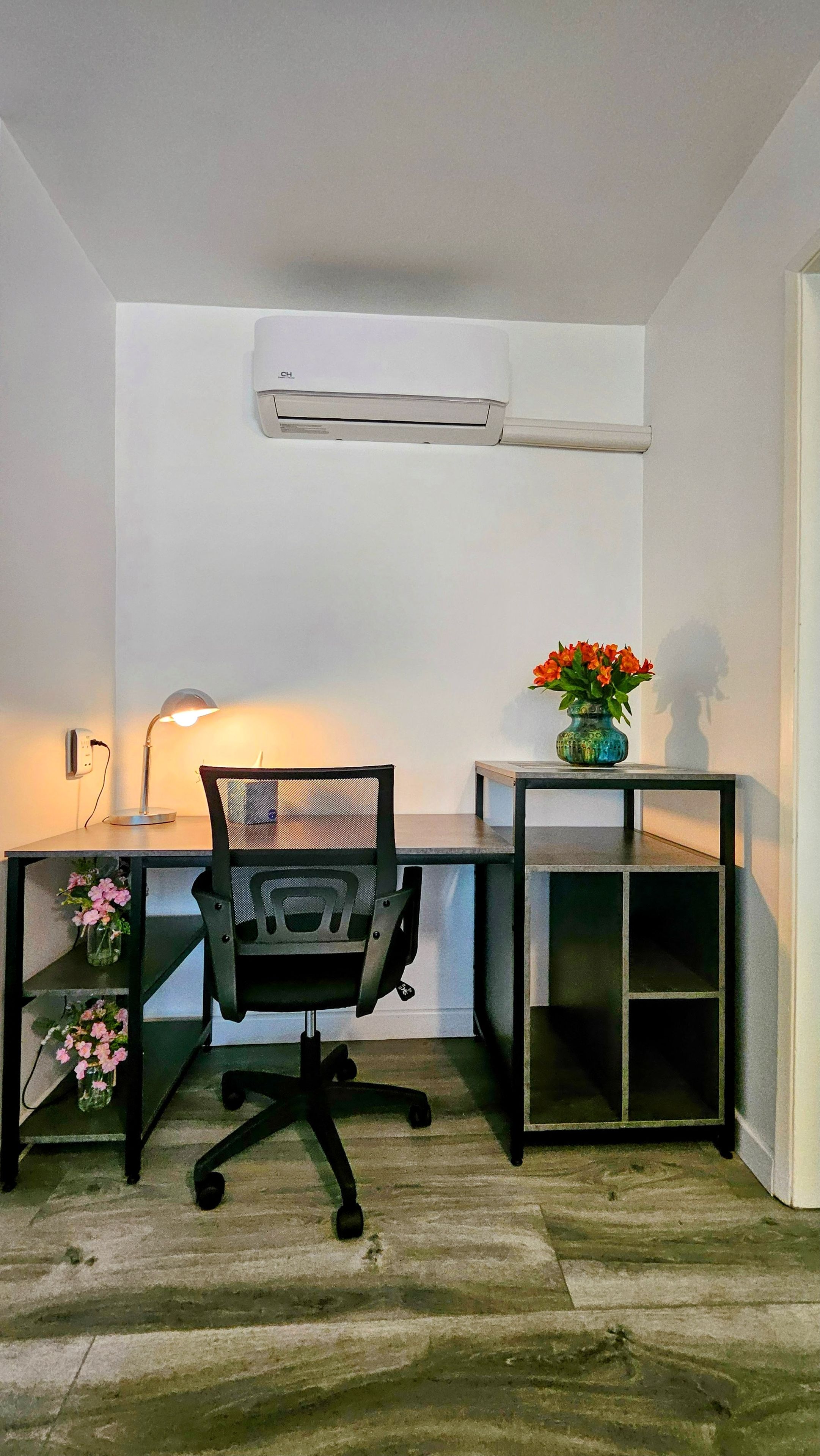 A workspace with a desk, chair, and a wall-mounted air conditioner.