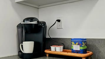 Een keuken met een magnetron, koffiezetapparaat en een dienblad met bekers en een bak.
