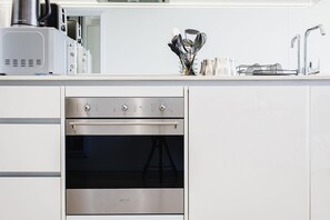 A modern kitchen with a built-in oven, stainless steel appliances, and a countertop with kitchen utensils.