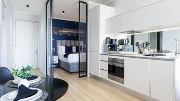 A modern apartment with a kitchen, dining area, and a bedroom with a cityscape view.