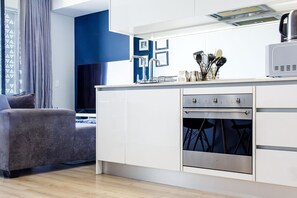 A modern kitchen with a built-in oven, a microwave, and a dining area with a grey sofa.