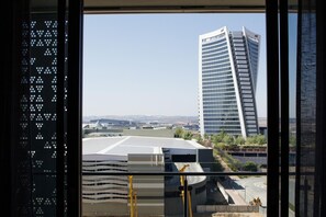 A view of a modern building with a unique angular design, a large parking area, and a clear sky.