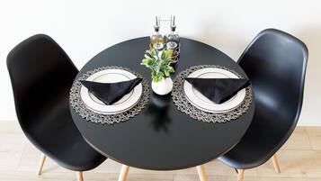A round table with two black chairs, each with a white plate and a black napkin.
