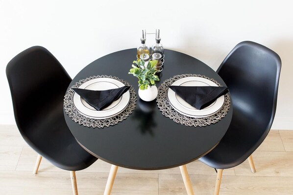 A round table with two black chairs, each with a white plate and a black napkin.
