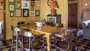A wooden-paneled room with a checkered floor, a wooden dining table with chairs, and a variety of framed pictures on the walls. - New: Quitch Cottage - steps from the beach (Quindalup)