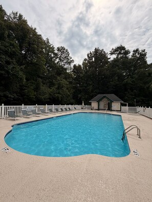 Una piscina rectangular amb una zona poc profunda, envoltada per una tanca blanca i gandules.