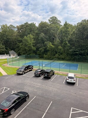 A parking lot with a tennis court surrounded by trees. - Coastal 2B condo minutes from the beach & attractions with pool and golf access! (Longs)