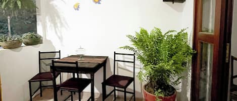 Un petit coin repas avec une table et des chaises en bois, une plante en pot et un mur agrémenté d’éléments décoratifs.