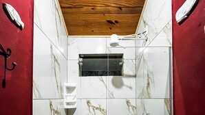 Casa de banho com teto de madeira, azulejos de mármore branco e zona de duche.